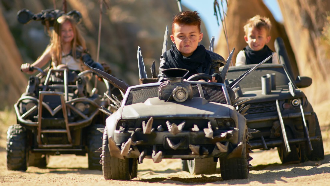 dzieci jadące pojazdami przypominającymi świat z filmu Mad Max